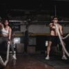 man and woman holding battle ropes