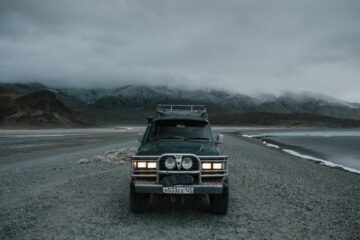 car parked on seashore near mountains in foggy weather