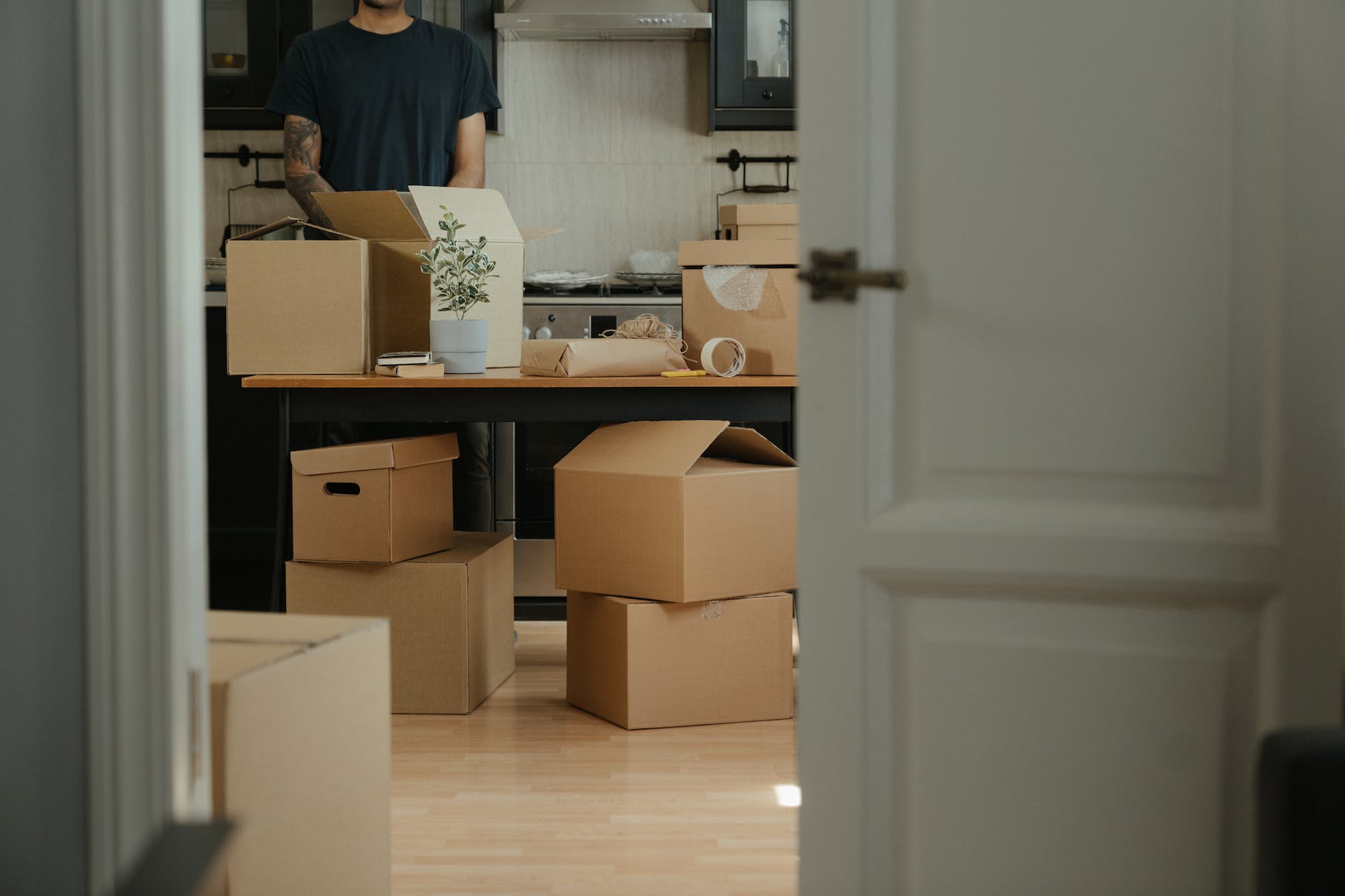 man in black shirt standing near brown cardboard boxes