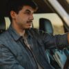 serious young guy driving car at sundown