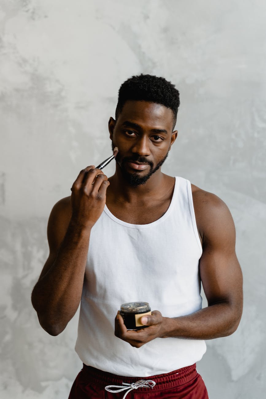 man in white tank top holding black and silver can